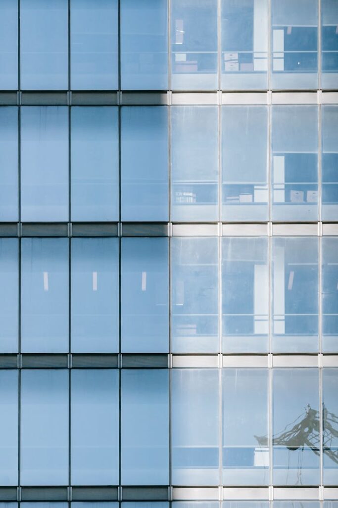 High multistory commerce building with reflecting glass windows covered with roller blinds from sunlight